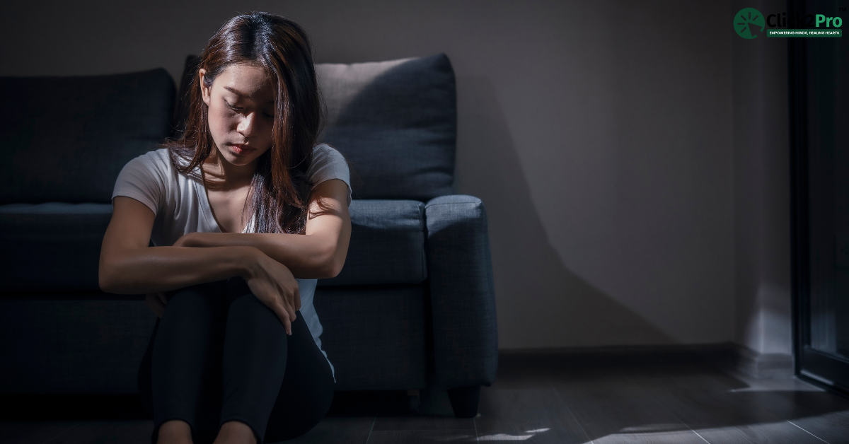 Young woman sitting alone in low light, appearing sad and introspective, related to Histrionic Personality Disorder.