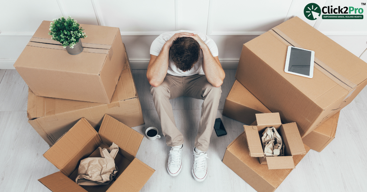Stressed man surrounded by moving boxes, illustrating the mental strain of major life changes.