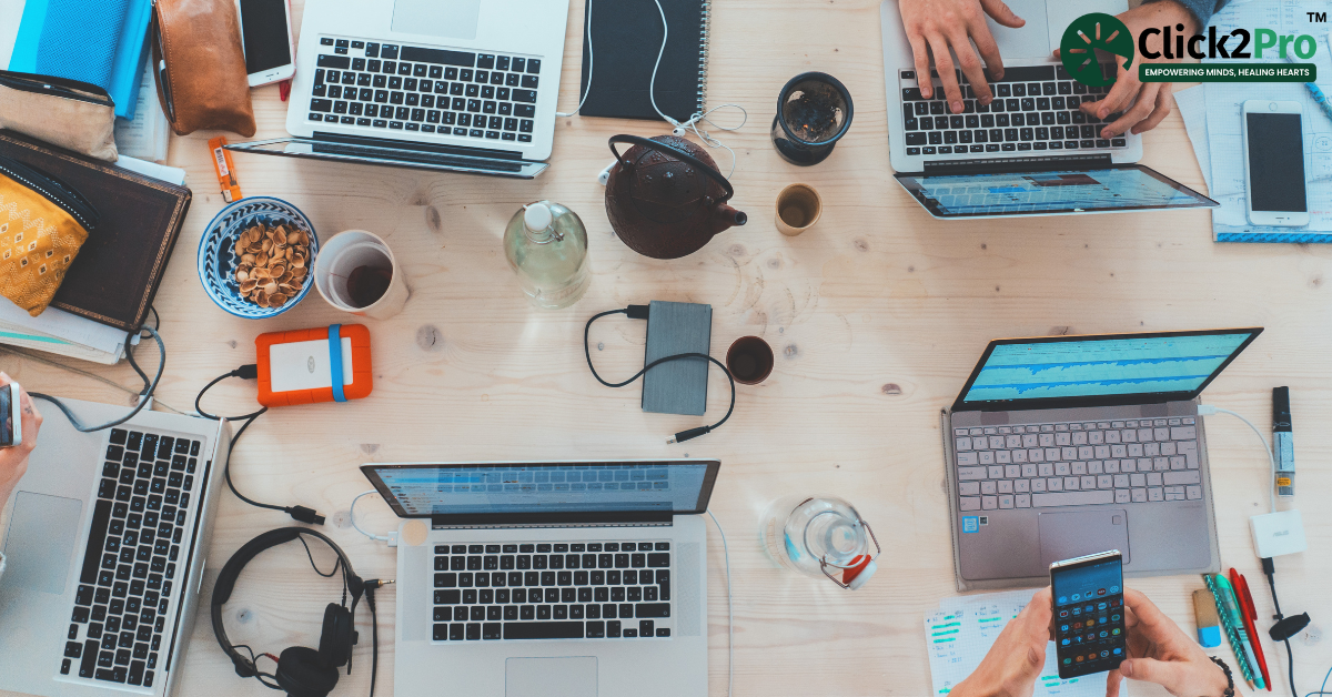 Digital workspace setup with multiple laptops and devices illustrating technology’s role in mental health.